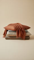 Burnt terracotta linen throw, 3/4 angle as default for bedding stacks, throws, and cushions — allows depth and reveals...
