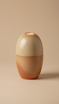 A decorative ceramic table lamp with a smooth, organic shape, centered in the frame against a Soft Almond background. The...