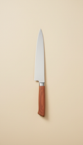 Signature stainless steel chef's knife, Three-quarter angle shots at slight downward tilt (just above eye-level), placing...