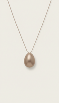 Minimalist Soft Taupe pendant necklace, Hero jewelry pieces captured at 3/4 angle on matte plinths or trays, allowing...